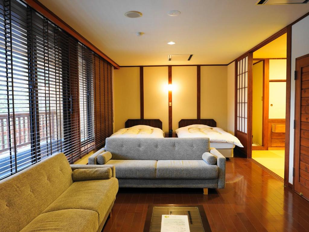 un salon avec un canapé et un lit dans l'établissement Tomuraushionsen Higashi Taisetsuso, à Shintoku