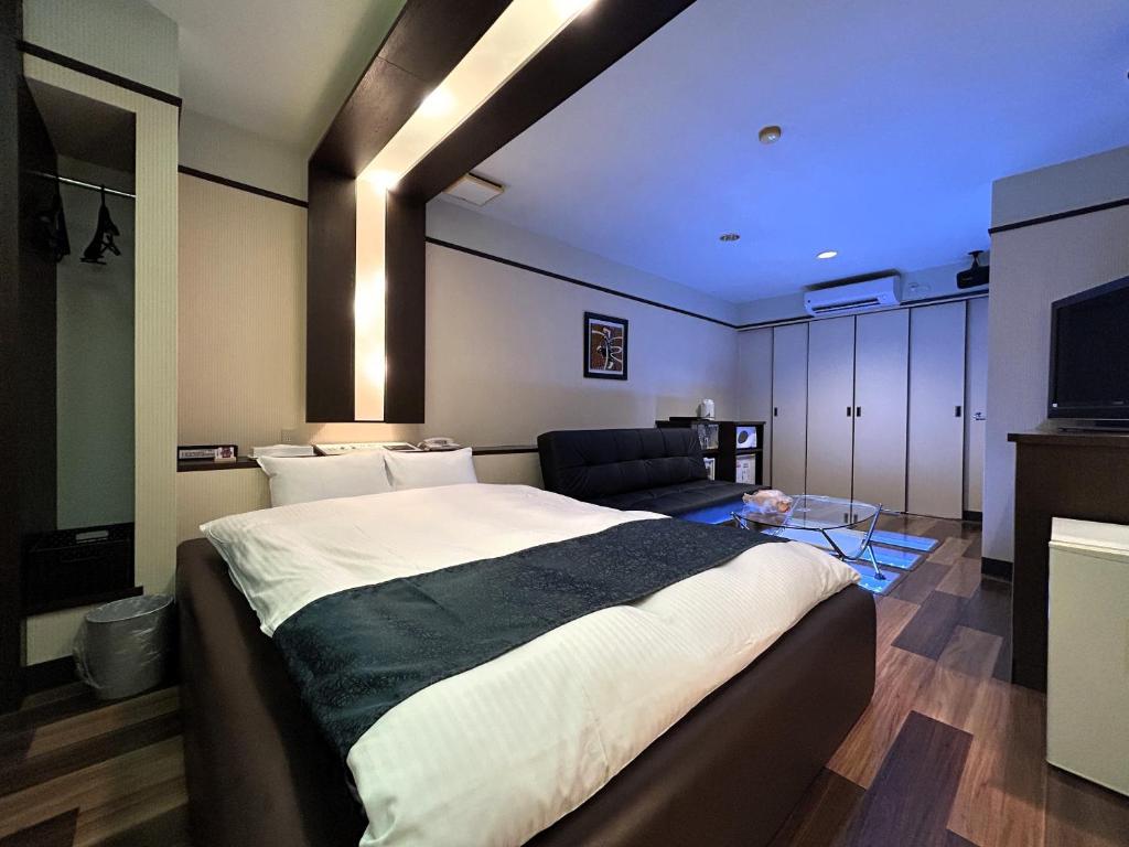 une chambre avec un grand lit et un canapé dans l'établissement Hotel MGM, à Niigata