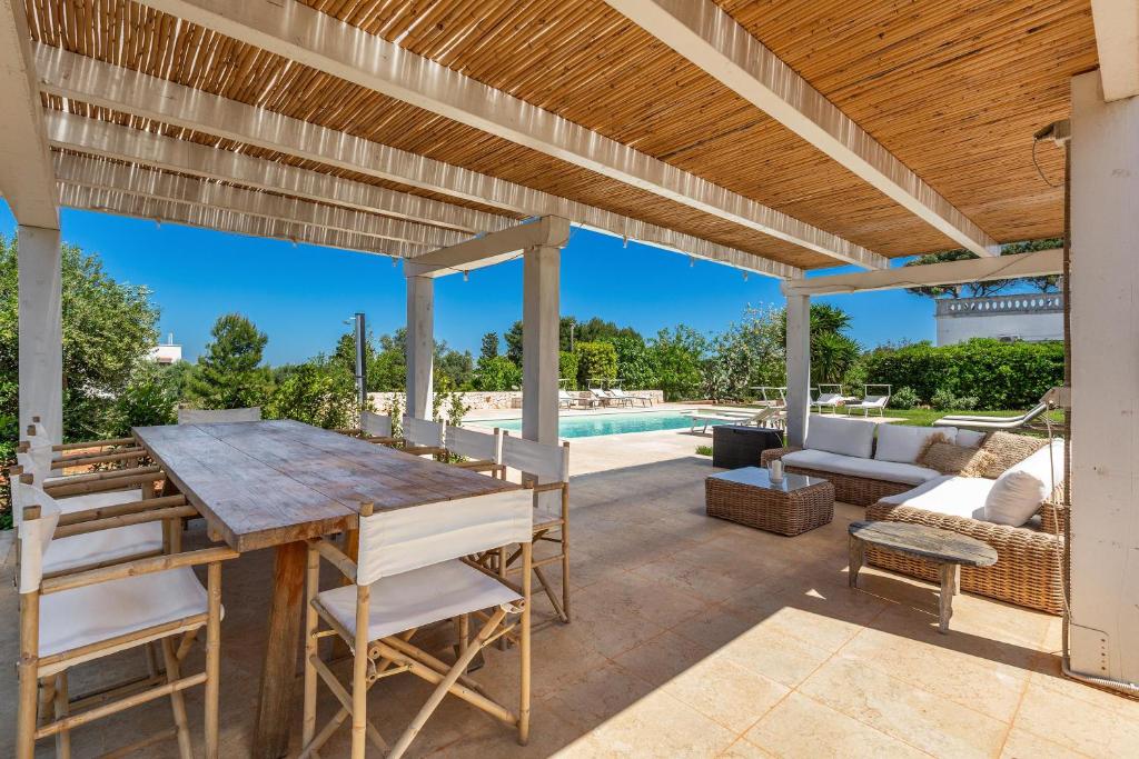 un patio avec une table et des chaises et une piscine dans l'établissement Casal 800 by Perle di Puglia, à Ostuni