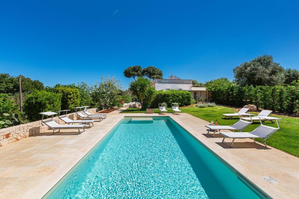 une piscine avec des chaises longues et une visière de piscine dans l'établissement Casal 800 by Perle di Puglia, à Ostuni
