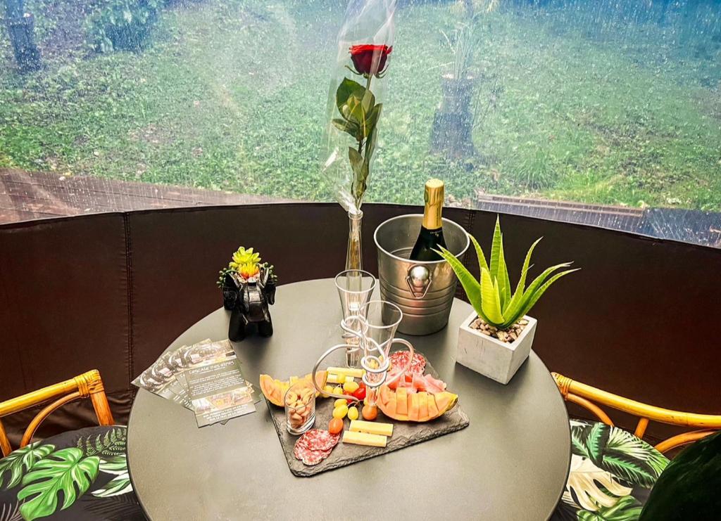 une table avec une assiette de nourriture et un verre de vin dans l'établissement Logement insolite "Bubble jungle", à Saint-Évarzec