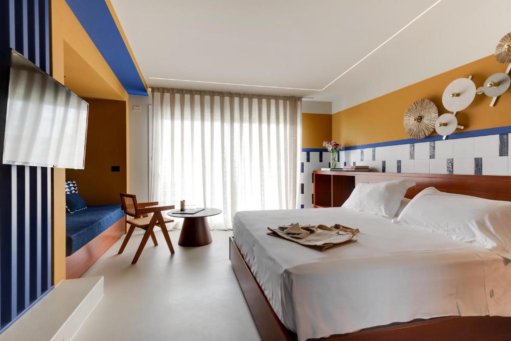 - une chambre avec un lit blanc et un mur bleu et jaune dans l'établissement MARITTIMO Milano Marittima, à Milano Marittima
