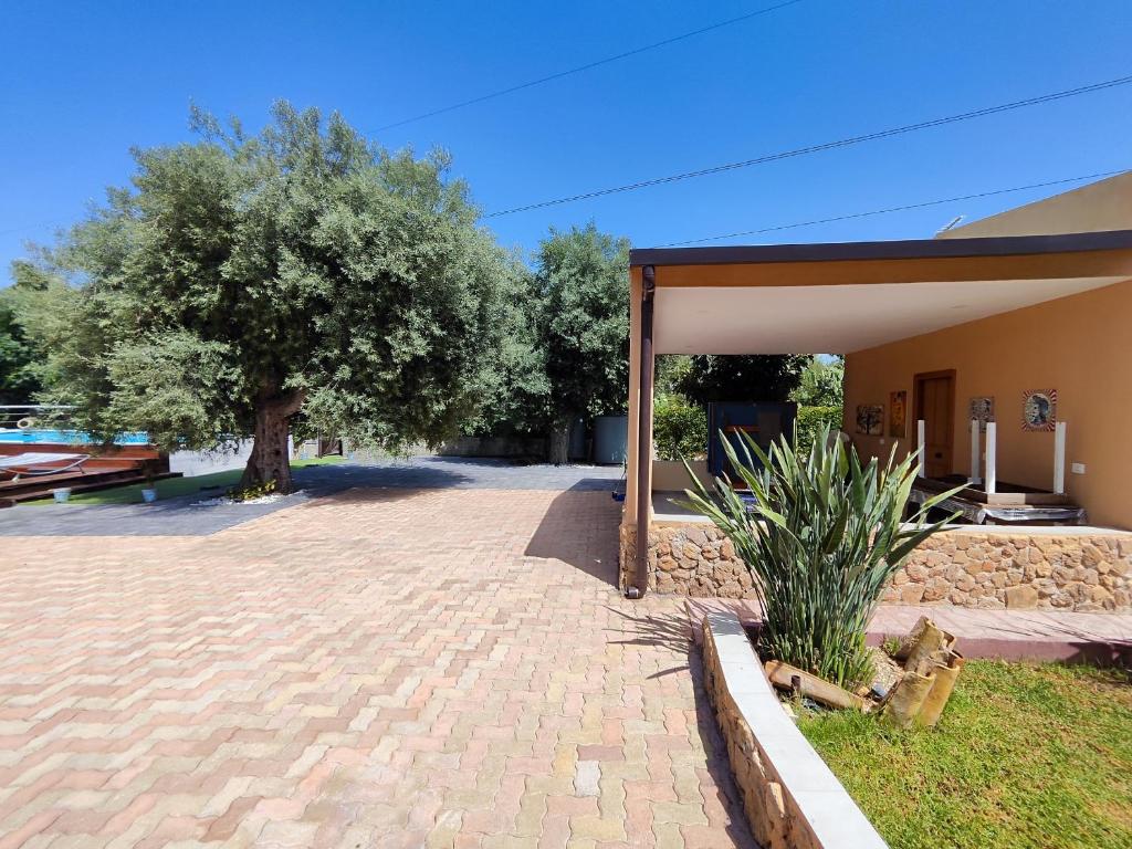 un bâtiment avec un arbre et une allée en briques dans l'établissement Puffolandia House, à Contrada Maeggio