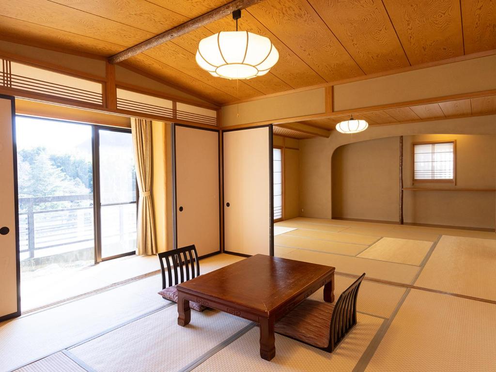 Cette chambre dispose d'une table en bois et d'une grande fenêtre. dans l'établissement Izu Nagaoka Kinjokan, à Izunokuni