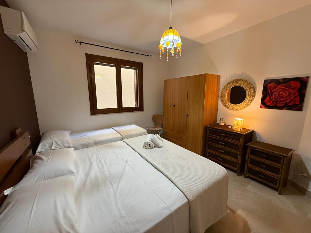 - une chambre avec un grand lit blanc et un lustre dans l'établissement Le Case di Palma - Villa Maria, à Custonaci