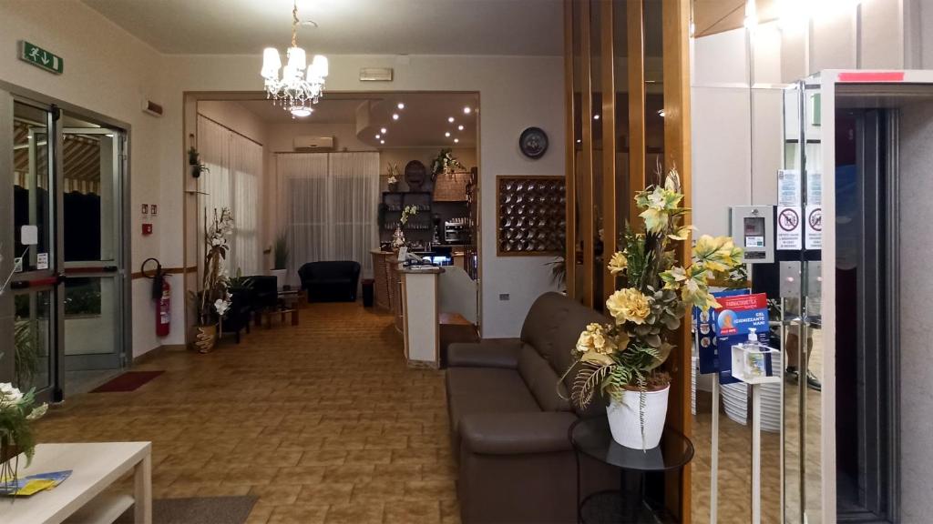 un salon avec un canapé et une table avec des fleurs dans l'établissement Hotel La Caravella, à Bellaria-Igea Marina