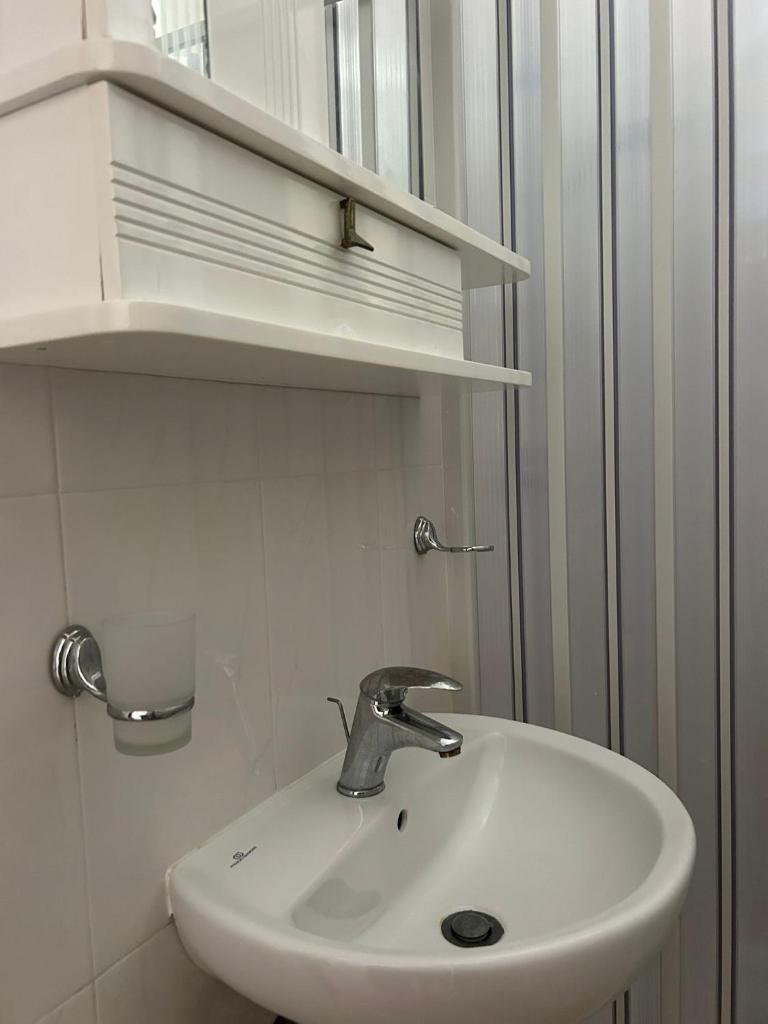 un lavabo blanc dans une salle de bain avec des étagères dans l'établissement Appartamenti Vacanze Minervino, à Vieste