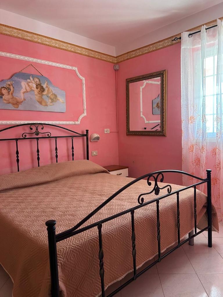 - une chambre avec un grand lit aux murs roses dans l'établissement Appartamenti Vacanze Minervino, à Vieste