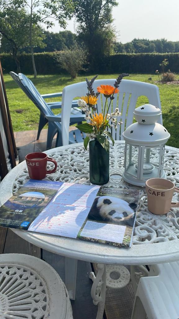 une table blanche avec un vase de fleurs sur elle dans l'établissement Le Nid du Tui, à Faverolles