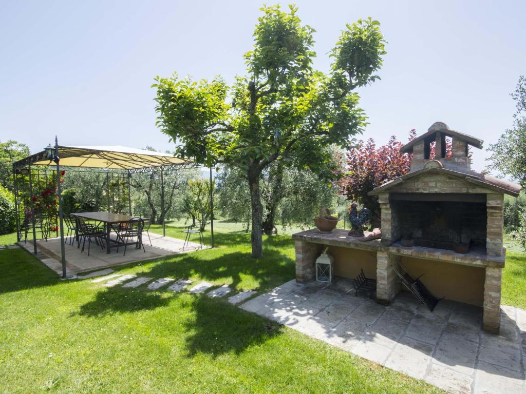 une arrière-cour avec une cheminée en pierre et une table de pique-nique dans l'établissement Maestà Del Sasso, à Cortone