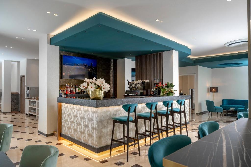 un bar dans le hall de l'hôtel avec des tabourets verts dans l'établissement Hotel Grazia Riccione, à Riccione