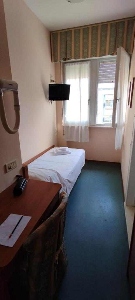 une chambre avec deux lits, un bureau et une fenêtre dans l'établissement Hotel Acerboli, à Rimini