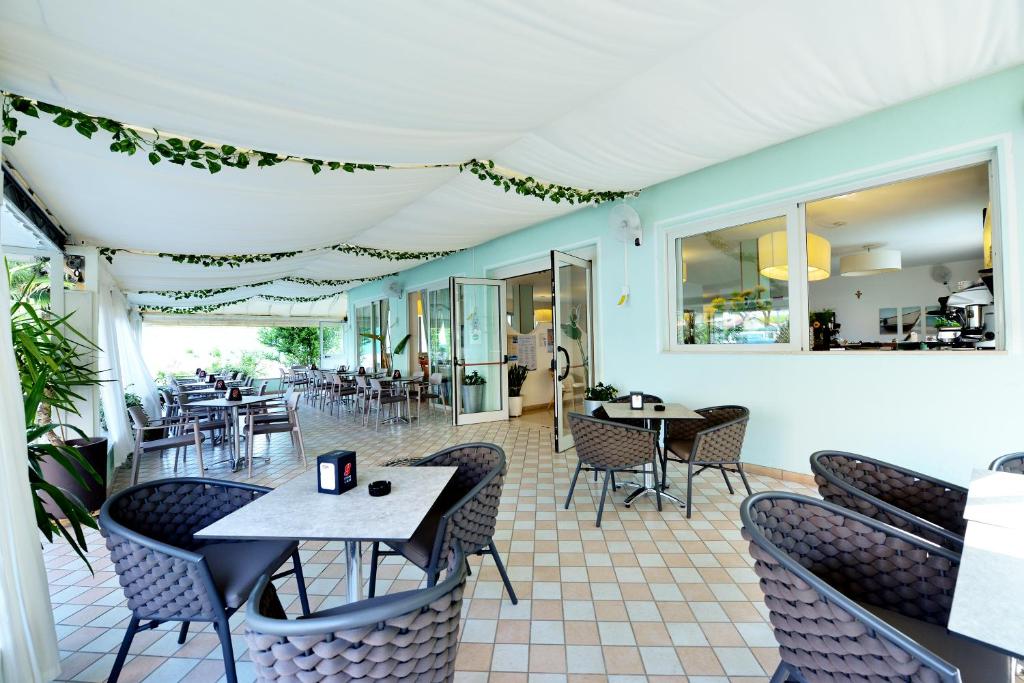 un restaurant avec des tables, des chaises et des fenêtres dans l'établissement Hotel Itta, à Caorle