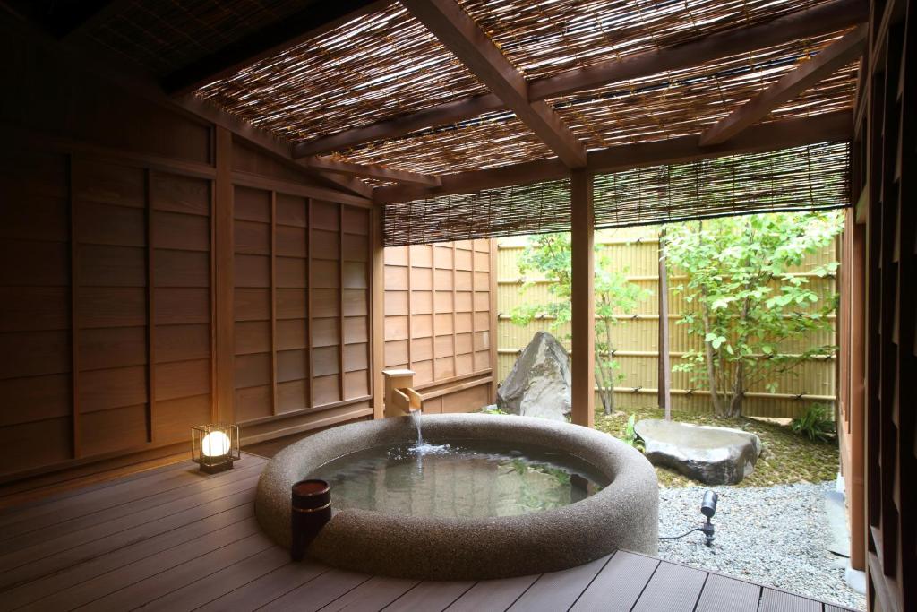 une chambre avec une baignoire au milieu d'un patio dans l'établissement Kanazawa Yuwaku Onsen Kokarian, à Kanazawa