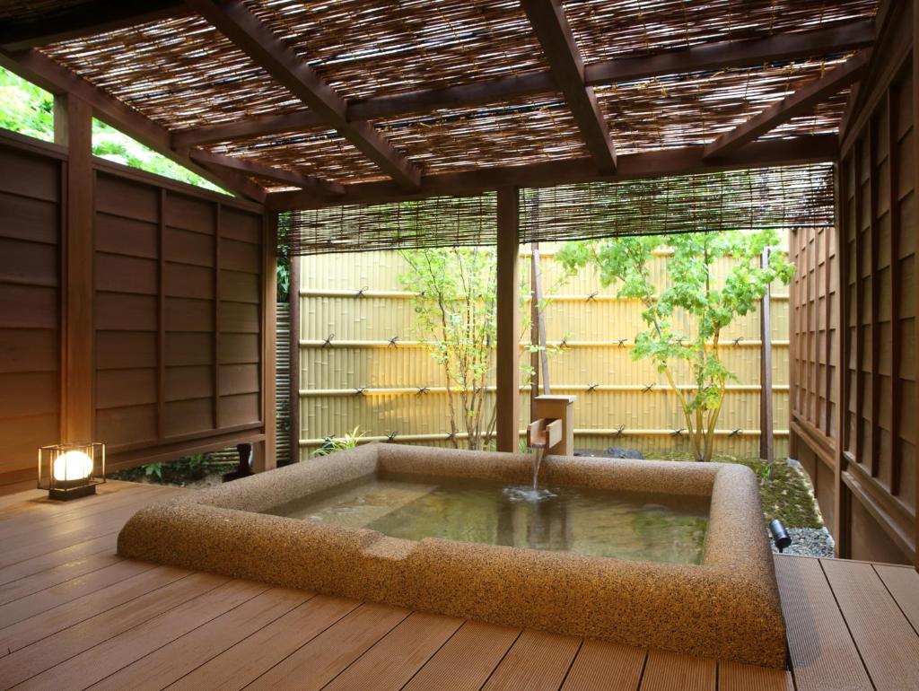une baignoire jacuzzi au milieu d'un patio dans l'établissement Kanazawa Yuwaku Onsen Kokarian, à Kanazawa