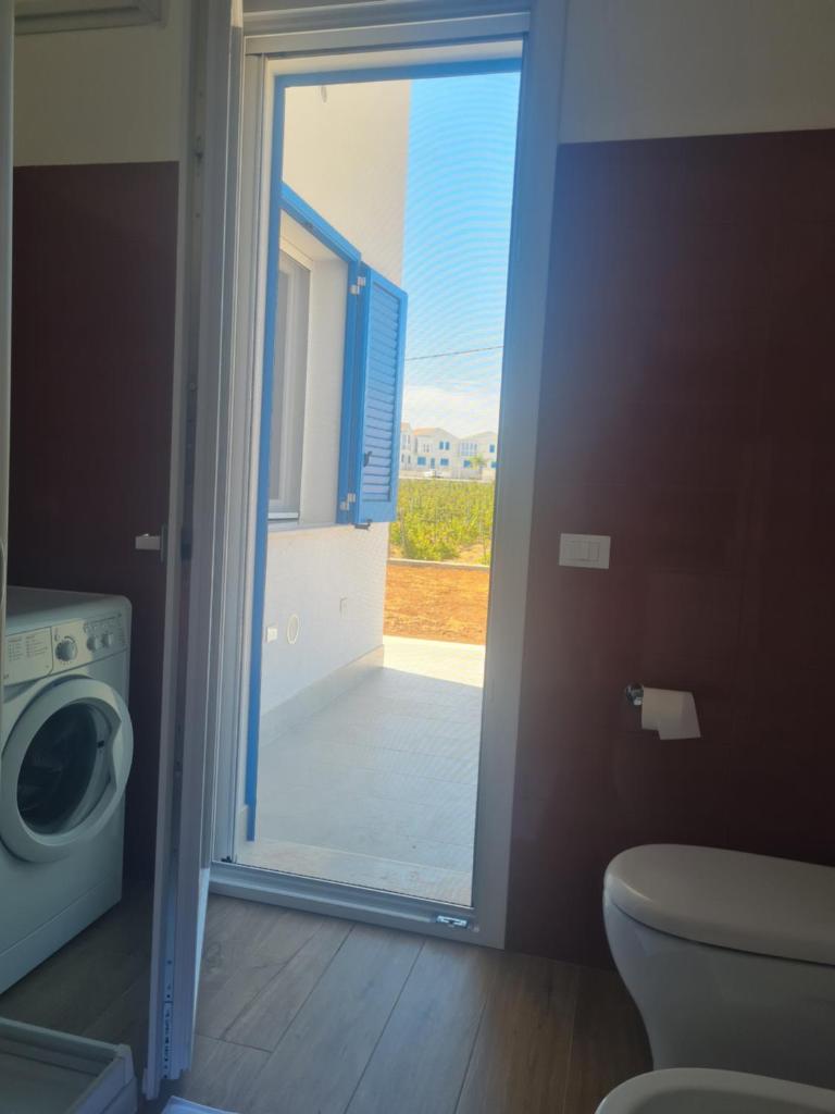 La salle de bains est pourvue d'un lave-linge et d'une porte en verre. dans l'établissement Le Saline di San Francesco, à Marausa