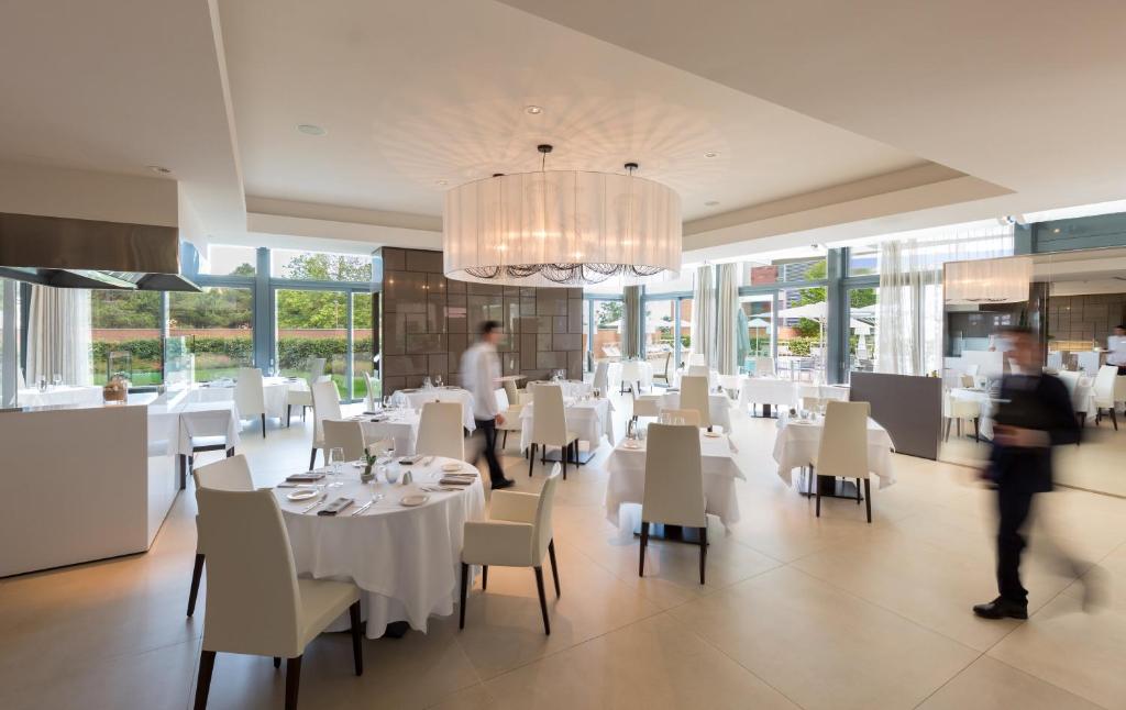 une salle à manger avec des tables et des chaises blanches et un lustre dans l'établissement Almar Lido Jesolo, à Lido di Jesolo