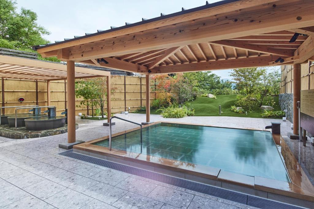 une piscine extérieure sous une pergola en bois dans l'établissement Hotel Yumeshizuku, à Minami Aso