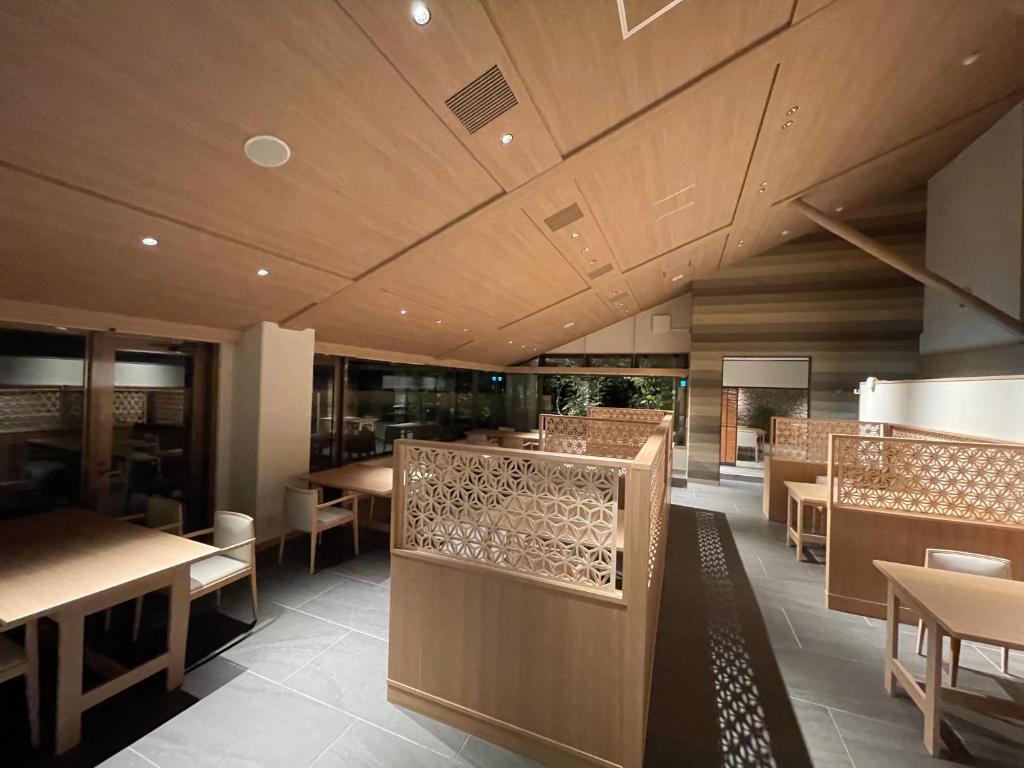 un restaurant avec des tables et des chaises et un plafond dans l'établissement Hotel Yumeshizuku, à Minami Aso