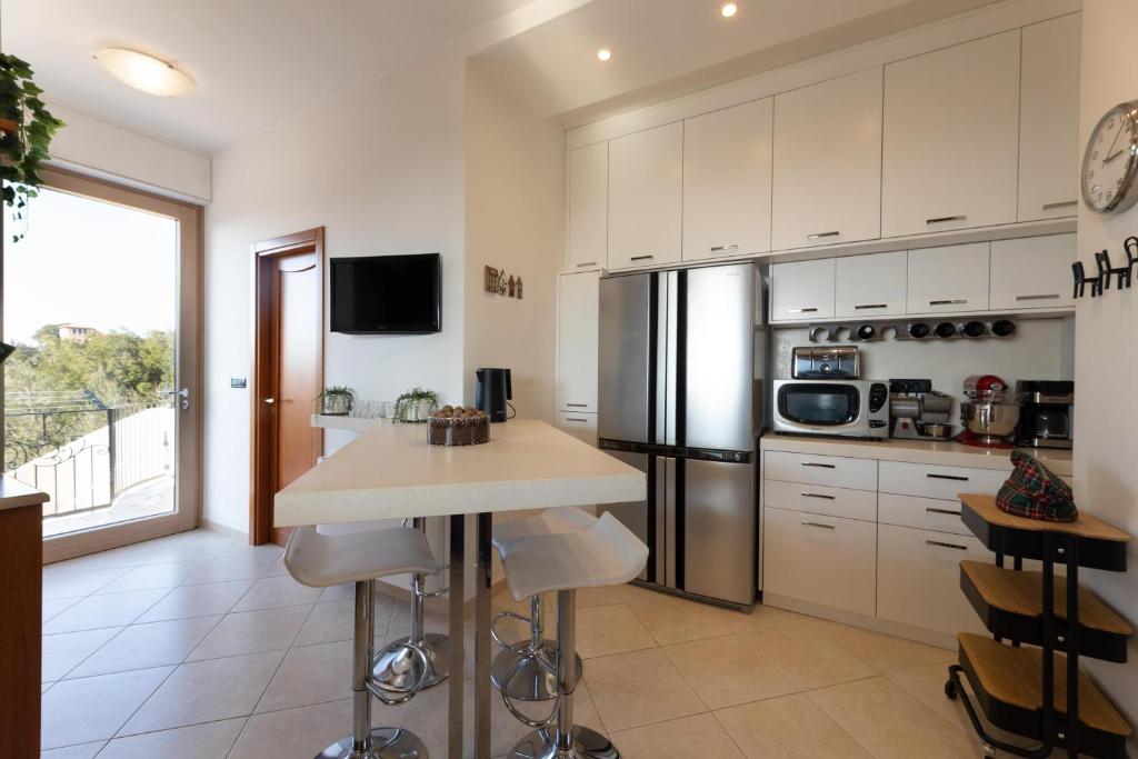 une cuisine avec des armoires blanches et un réfrigérateur en acier inoxydable dans l'établissement Villa Gentileschi, à Casarano