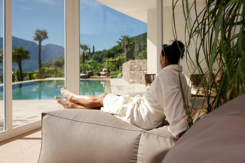 une femme assise sur un canapé donnant sur une fenêtre dans l'établissement Hotel Haus am Hang, à Caldaro