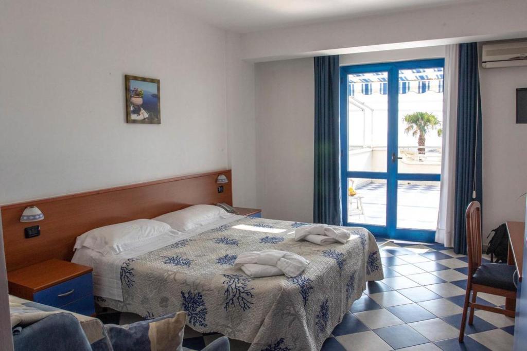 une chambre avec un lit et une porte coulissante en verre dans l'établissement Hotel San Gaetano, à Grisolia