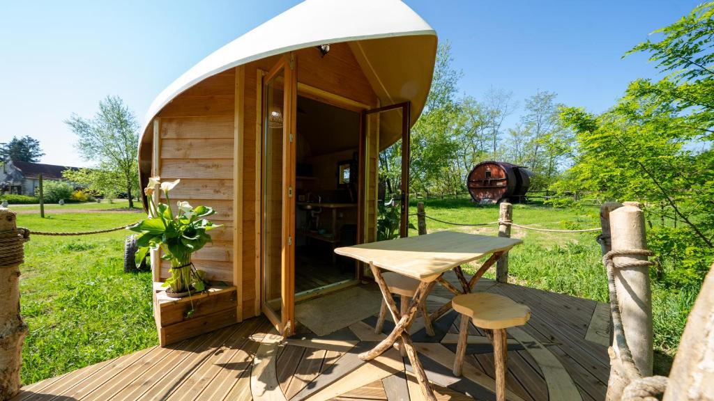 une yourte avec une table et des chaises sur une terrasse dans l'établissement Village Toue du Domaine des Demoiselles, à Chassenard