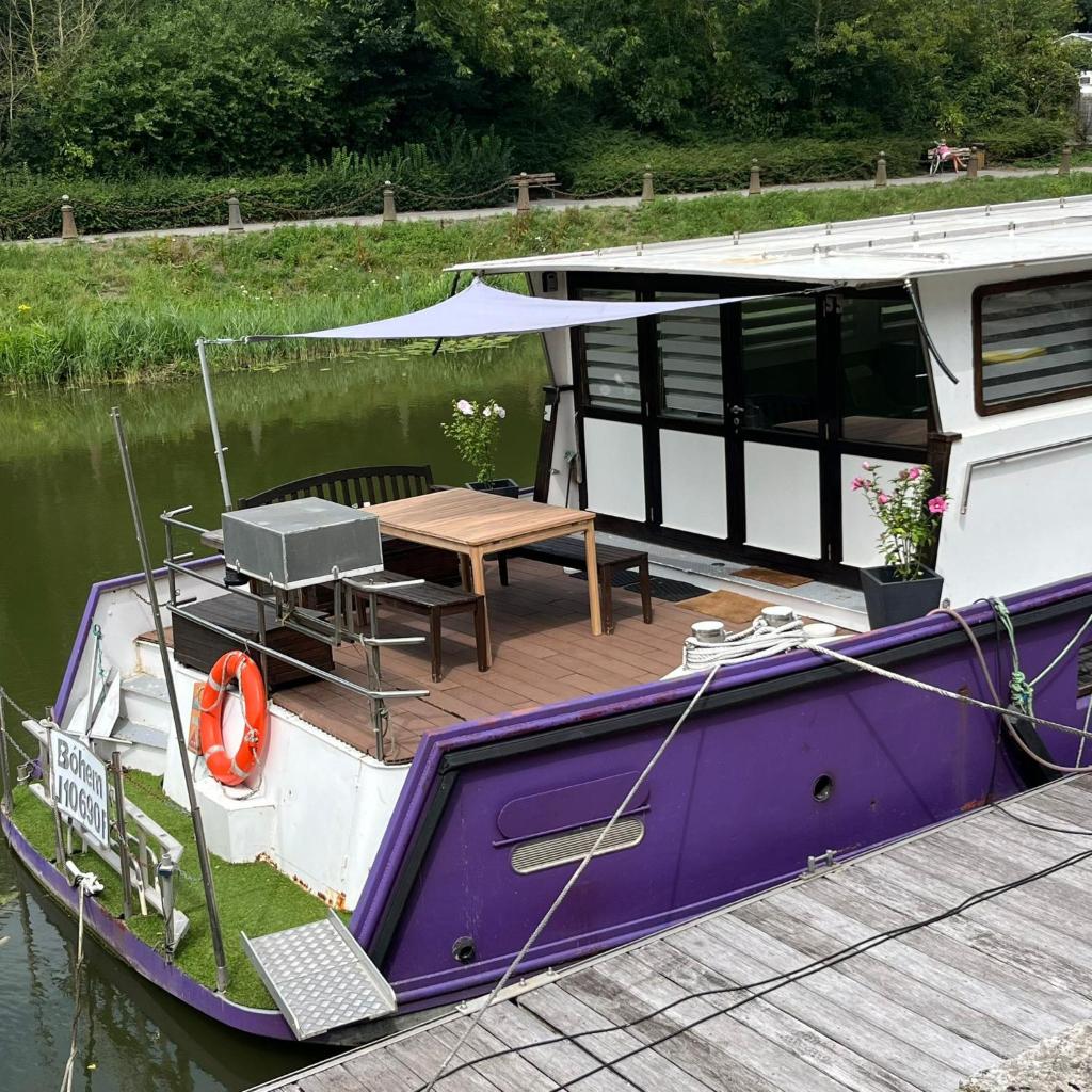 un bateau violet et blanc avec une table sur l'eau dans l'établissement Nuit insolite à bord d'une péniche, 6 personnes, à Bergues