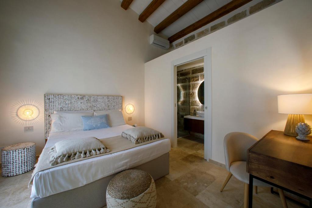 - une chambre avec un grand lit, un bureau et un lit dans l'établissement La Dimora del Sale - Ville con piscina, à Favignana