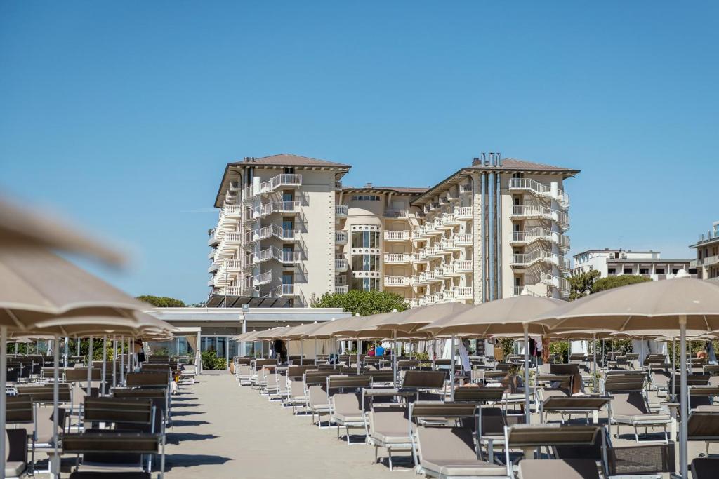 une rangée de chaises et de parasols sur une plage dans l'établissement Palace Hotel, à Milano Marittima