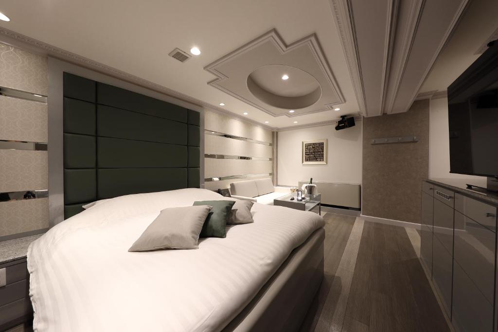 - une chambre avec un grand lit blanc et une télévision à écran plat dans l'établissement Hotel Valentine Chiryu, à Chiryu