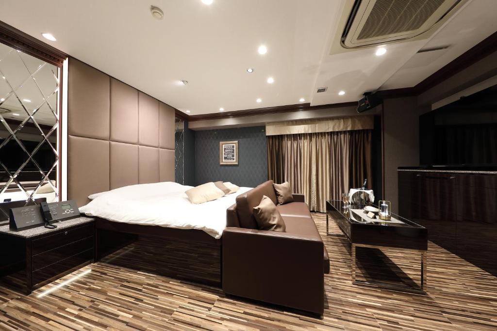 une chambre avec un lit, un canapé et un bureau dans l'établissement Hotel Valentine Chiryu, à Chiryu