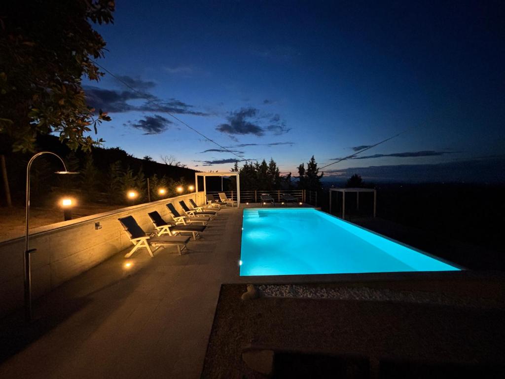 - une piscine avec des chaises et des lumières la nuit dans l'établissement Relais Portaluna delle Langhe, à Mango