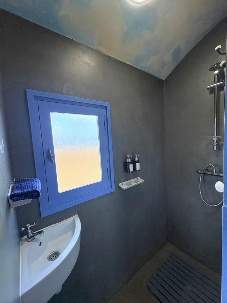 La salle de bains est pourvue d'une fenêtre bleue et d'un lavabo. dans l'établissement La roulotte CIRCUS des Grillots, à Beaulon