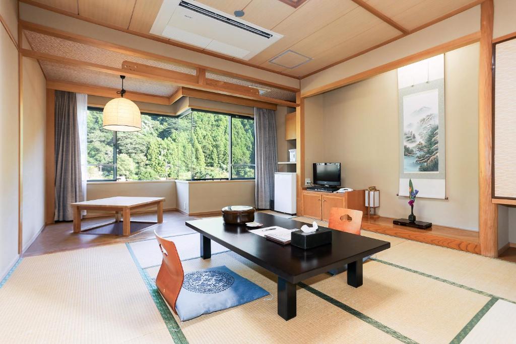 un salon avec une table, des chaises et une télévision dans l'établissement Ichinomata Onsen Kanko Hotel, à Shimonoseki