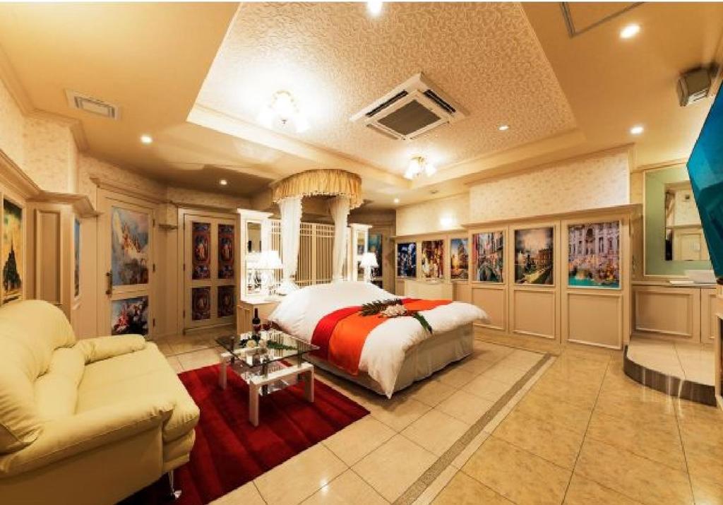 une grande chambre avec un lit et un canapé dans l'établissement 奈良生駒市ホテル567生駒店-Adult only 大人専用-, à Ikuma