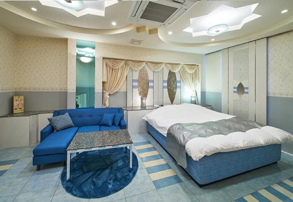 - une chambre avec un lit bleu et un canapé bleu dans l'établissement 奈良生駒市ホテル567生駒店-Adult only 大人専用-, à Ikuma