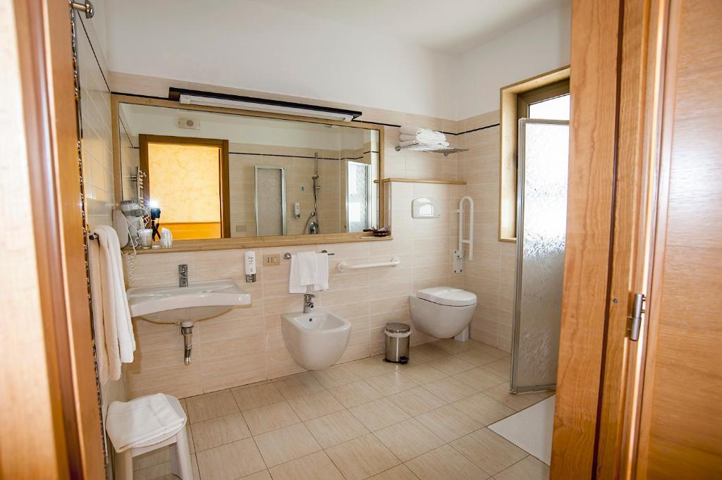 une salle de bain avec un lavabo, des toilettes et un miroir dans l'établissement Hotel La Tonnara, à Amantea