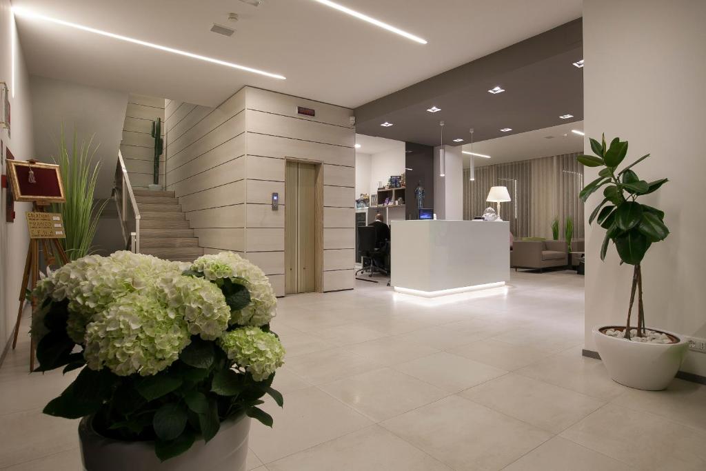 un hall d'entrée avec des fleurs et des escaliers dans un bâtiment dans l'établissement Hotel Derby S, à Lido di Jesolo