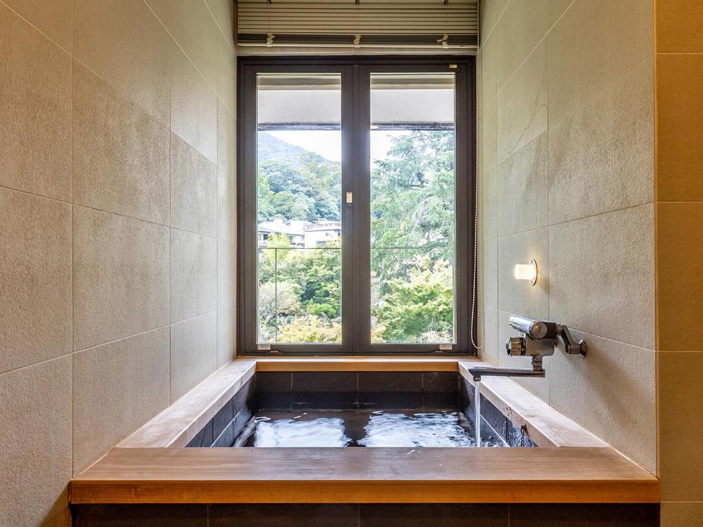 La salle de bains est pourvue d'une baignoire et d'une fenêtre. dans l'établissement Yoshiike Ryokan, à Hakone