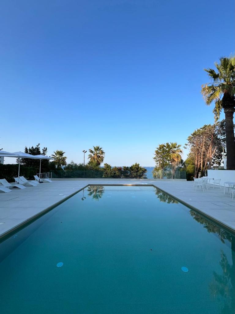 - une piscine avec des chaises et un palmier dans l'établissement Helios Hotel, à Crotone