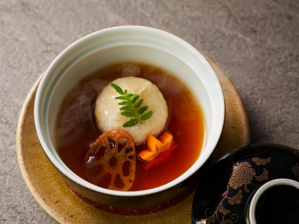 - un bol de soupe sur une assiette dans l'établissement KAMENOI HOTEL Arima, à Kobe