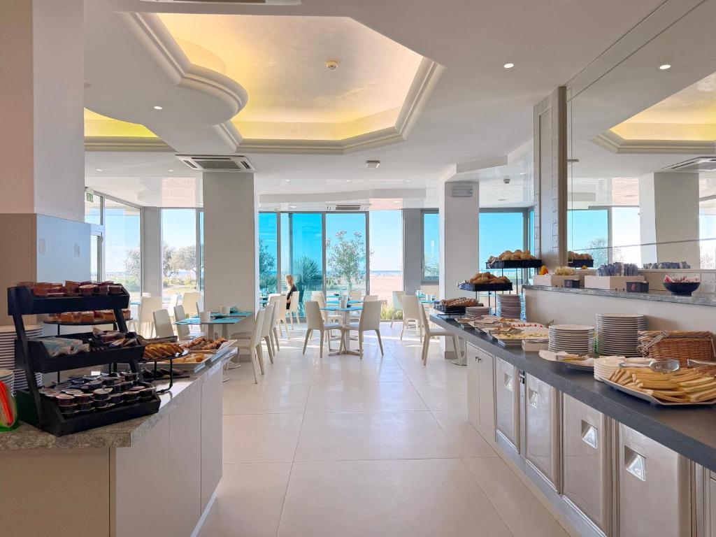un restaurant avec une ligne de buffet avec des tables et des chaises dans l'établissement Hotel Monaco, à Caorle