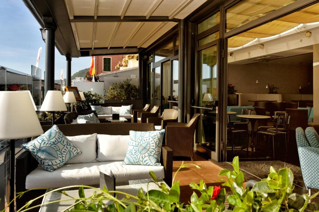 un patio avec un canapé, des tables et des chaises dans l'établissement Hotel Ligure, à Alassio