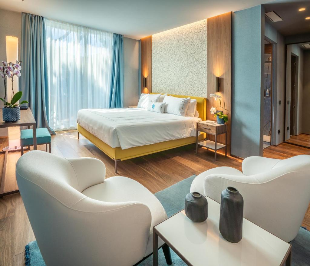 une chambre d'hôtel avec un lit et deux chaises dans l'établissement Gallia Palace Hotel - Relais & Châteaux, à Punta Ala