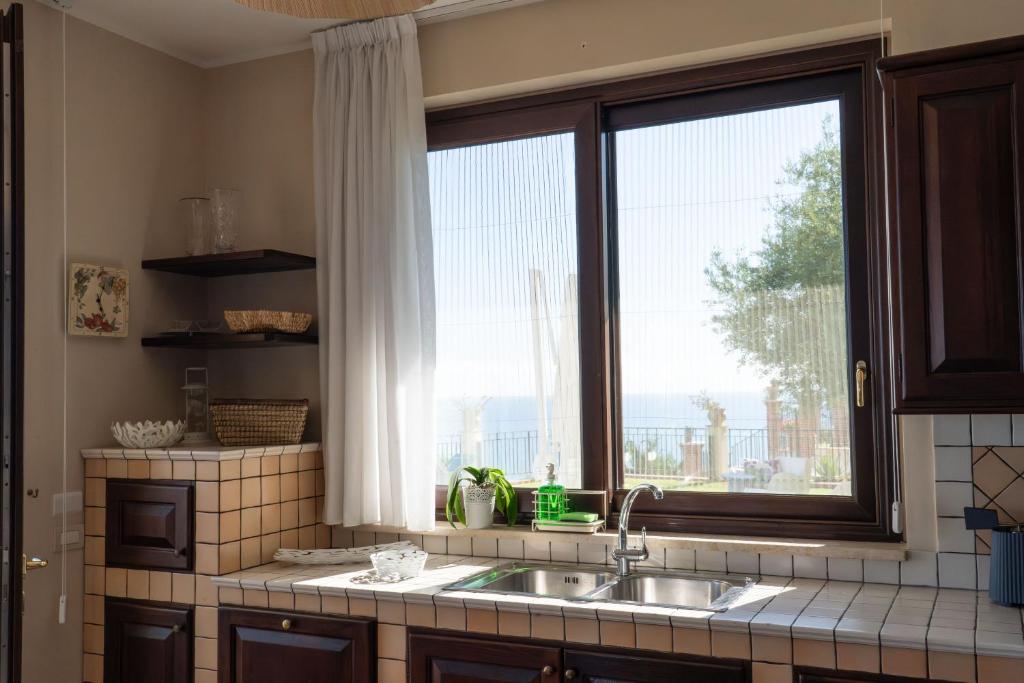 une cuisine avec un évier et une grande fenêtre dans l'établissement Villa Vale - with private pool and sea view, à Capo dʼOrlando