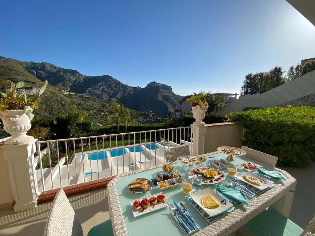 une table avec des assiettes de nourriture au sommet d'un balcon dans l'établissement Private modern villa in Taormina, à Taormine