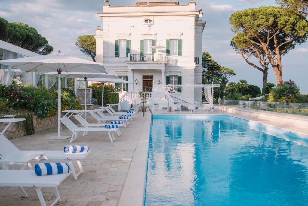 une piscine devant une maison blanche avec des chaises et un parasol dans l'établissement Villa Maria Teresa Boutique Hotel, à Formia 86 autres photos