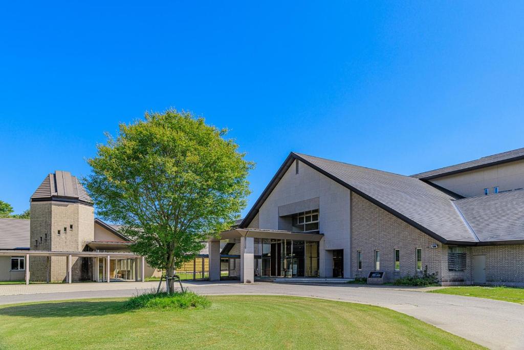 un grand bâtiment avec un arbre devant dans l'établissement Kyukamura Ura-Bandai, à Kitashiobara