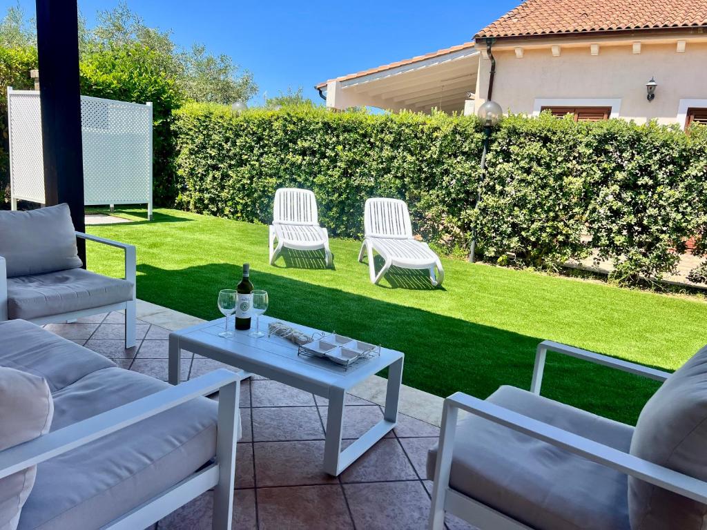 - une terrasse avec 2 chaises et une table avec une bouteille de vin dans l'établissement Villa Camelie, à Campofelice di Roccella